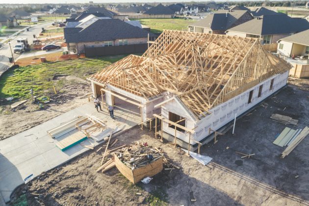 Drone photo of a house being constructed with workers walking up.
