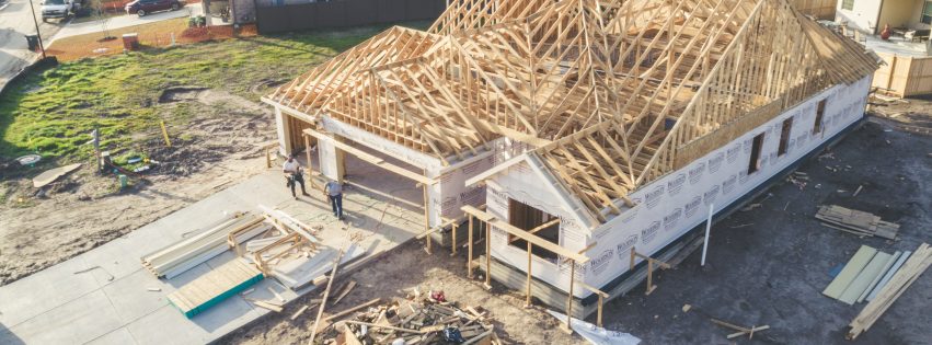 Drone photo of a house being constructed with workers walking up.