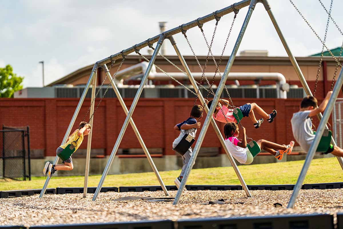 Children swing on a playground swing set at Neal Recreation Center in Bryan.