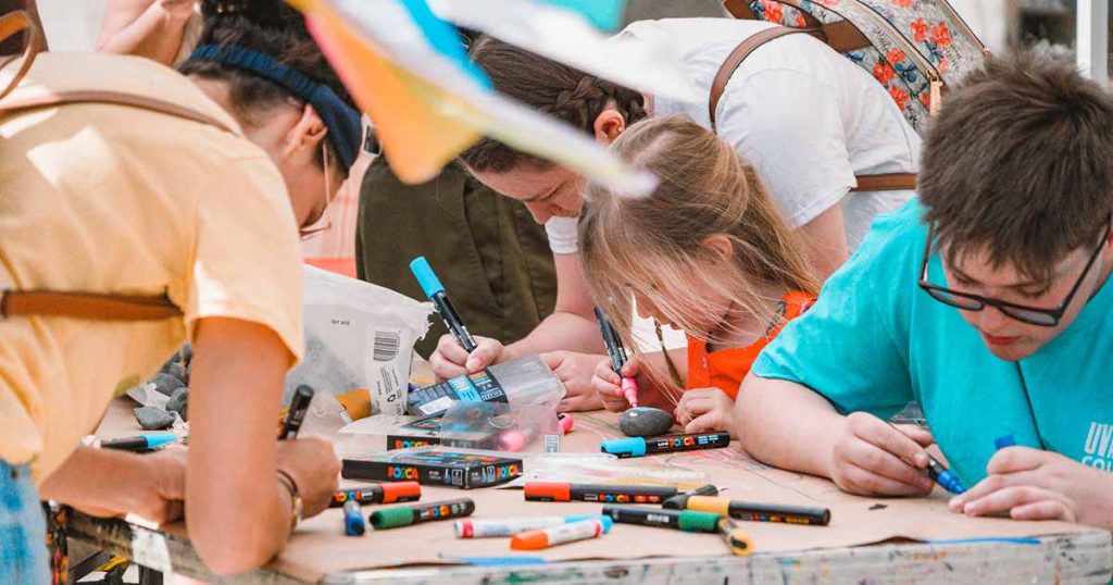 Children use markers to draw and write on a large piece of paper at the Downtown Bryan Street and Art Fair in 2023.