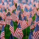field containing a large number of small American flags staked into the grass