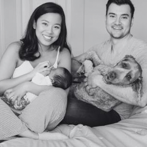 woman holding a baby sitting next to her husband holding a dog