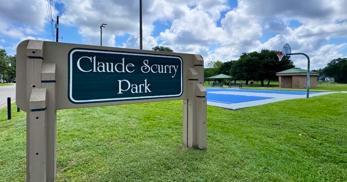 Claude Scurry Park sign with park in the background