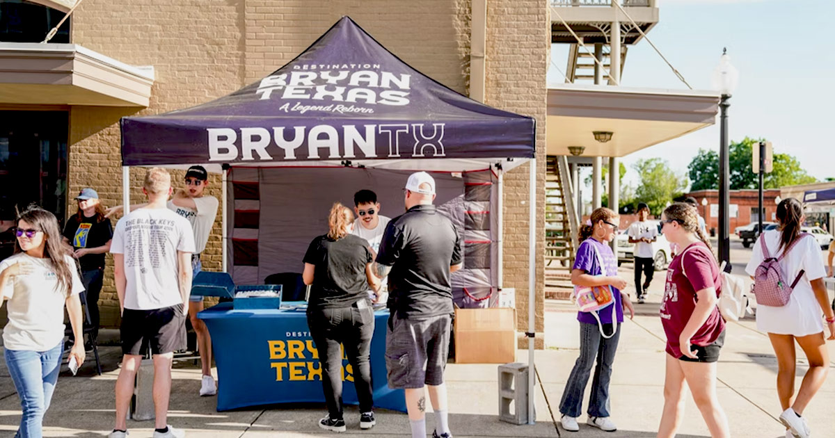 Destination Bryan market booth with logos and interested attendees surrounding the booth
