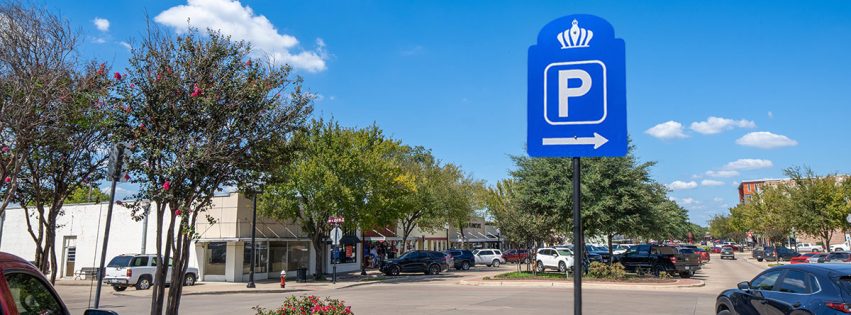 view down Main Street filled with parked vehicles behind a blue Bryan parking sign