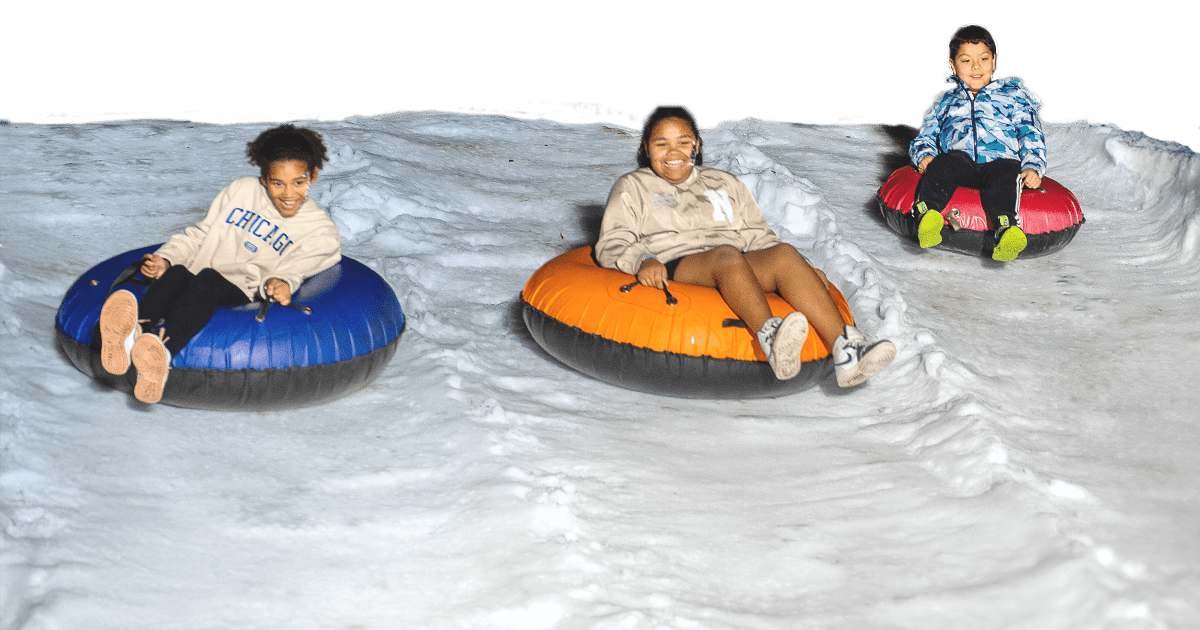 children riding down a snow hill in inflatable tubes